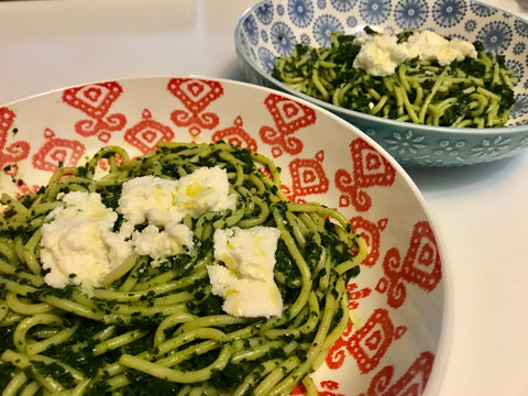 Two bowls of super green spaghetti topped with ricotta