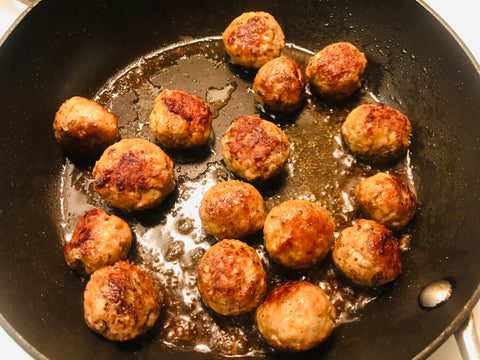 Sausage meatballs cooking in a frying pan