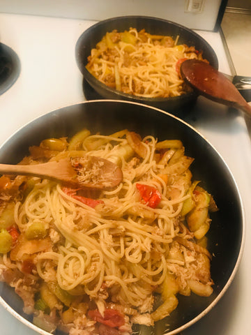 Two pans of fennel spaghetti, one with sausage the other with crab