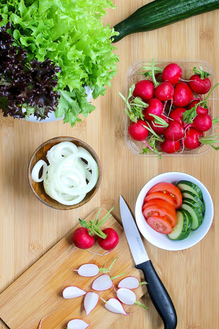 Fresh ingredients on a cutting board, lettuce, radishes, cucumbers, tomatoes, onions