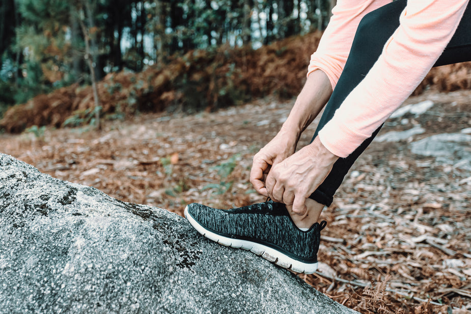 Woman tying her running shoes in the woods