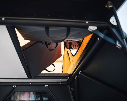 A person looking down through a tent side door and through the transform-a-floor down into the truck bed, showing accessibility of the tent