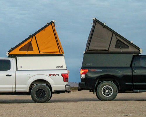 Two GFC Platform Campers parked back to back with the tents open to show the grey or orange tent color options