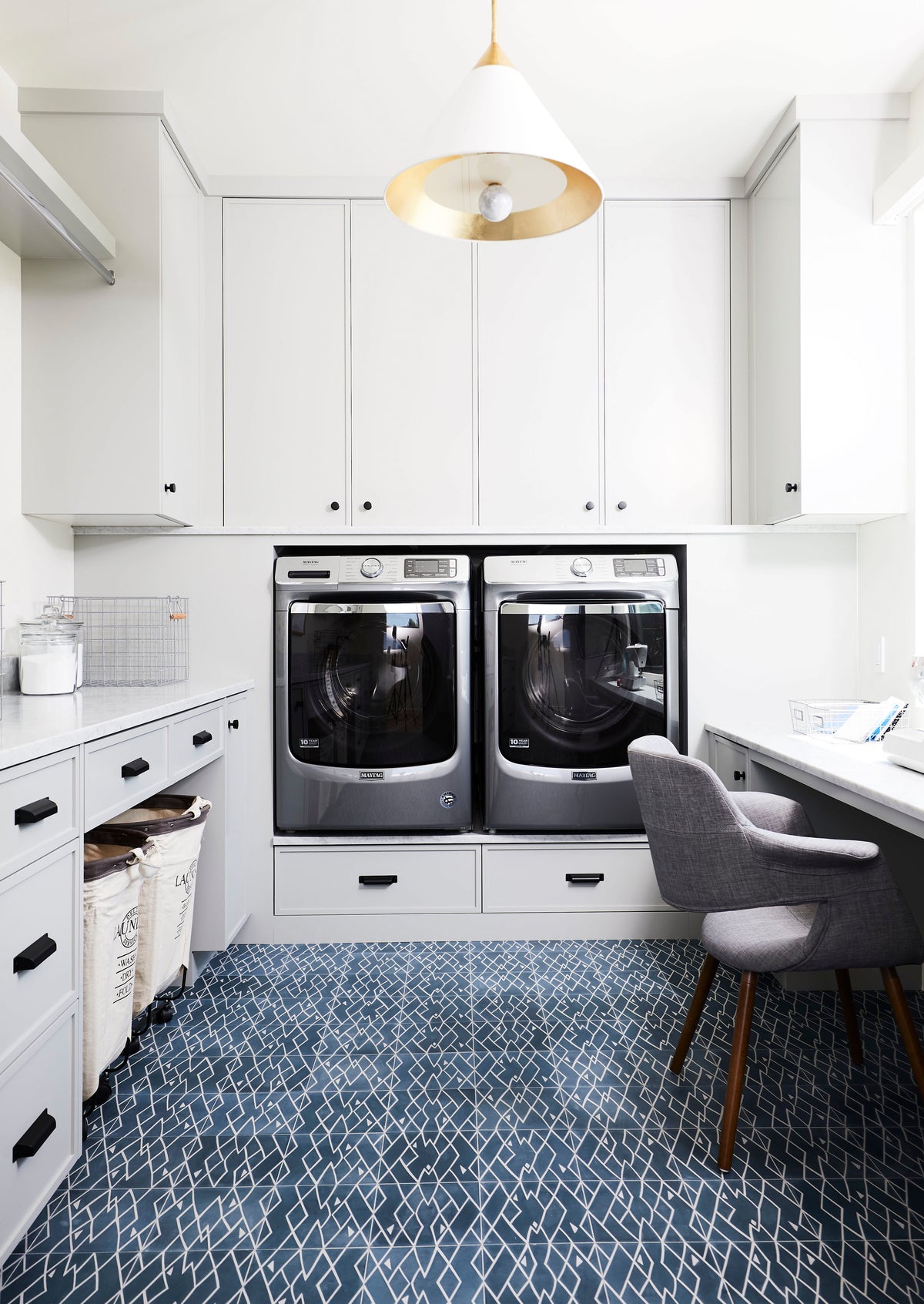 A laundry room/home office with a blue cement tile floor that looks like a rug.