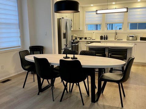 A White Oval Dining Table with Black Chairs around it