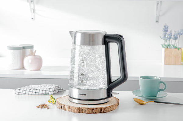 The 1.7 litre glass LED kettle on top of a clean countertop with a cup of coffee besides it.