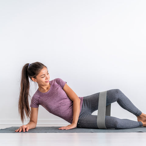Female athlete lying down stretching with a resistance band