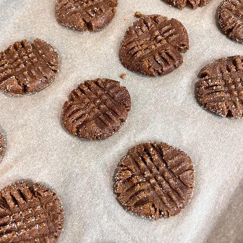 Gingersnap cookies on baking sheets flatten with fork lines in them