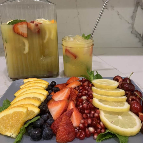 A pitcher with yerba mate and fruits. The platter contains oranges, strawberries, lemons and other fruits.