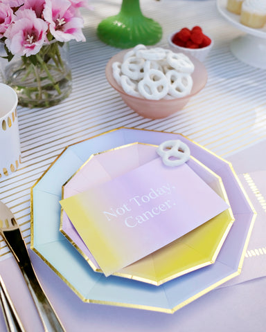 Pastel plates and note card atop gold pinstripe table runner
