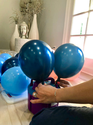 Two blue balloons being blowng up my portable dual nozzle.