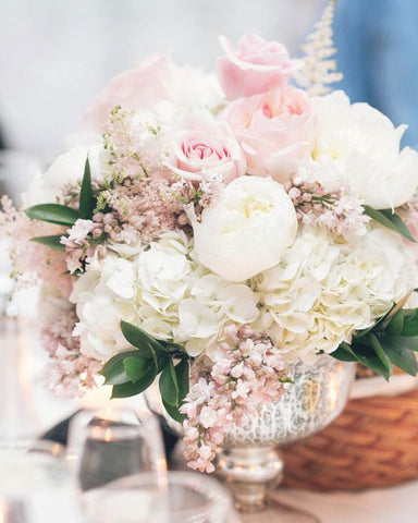 Pink and white floral bouquet or roses, hydrangeas and baby's breath in a silver vase.