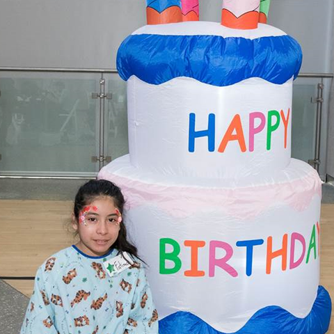 Little girl in front of a Happy Birthday inflatable balloon