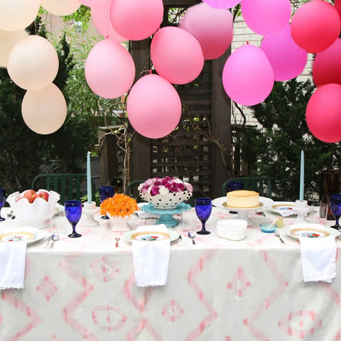 Ombre pink balloons hanging above a tablescape filled with flowers and desserts.