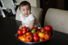 baby holding heirloom tomatoes