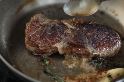 basting steak in butter with spoon 