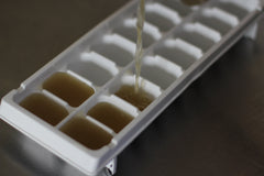 pouring chicken stock into ice cube tray