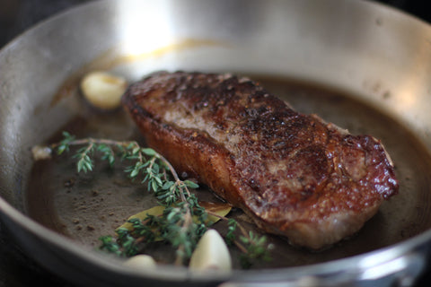 perfectly seared steak in pan with aromatics