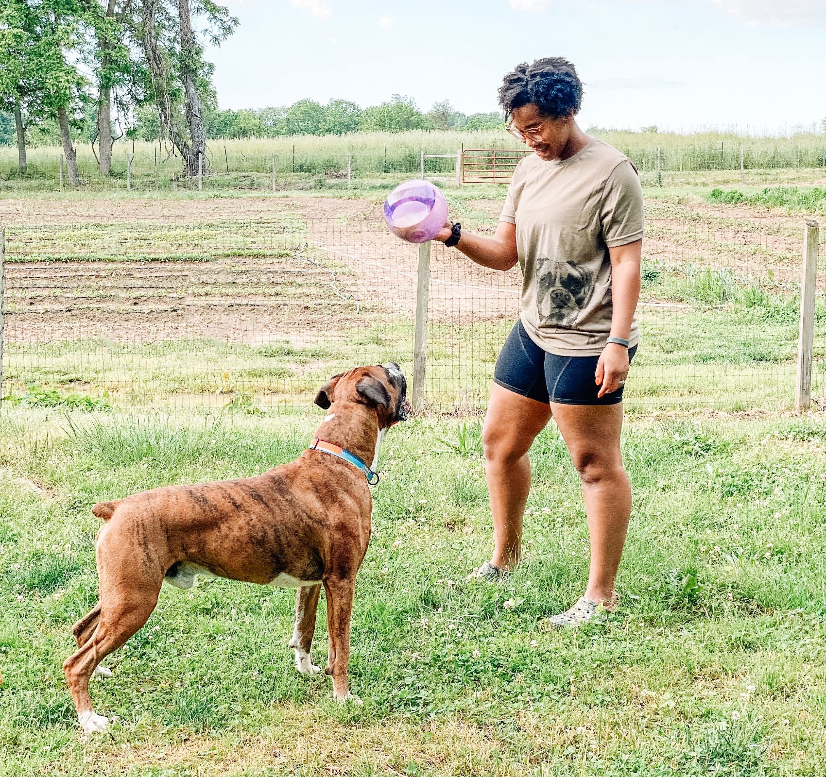 Woman wearing dog shirt while playing with her dog outside