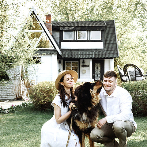 couple in front of home with dog