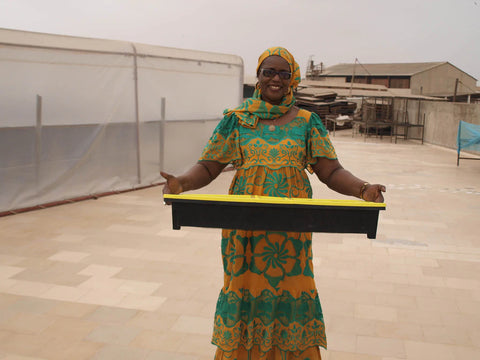 woman holds solar food dryer