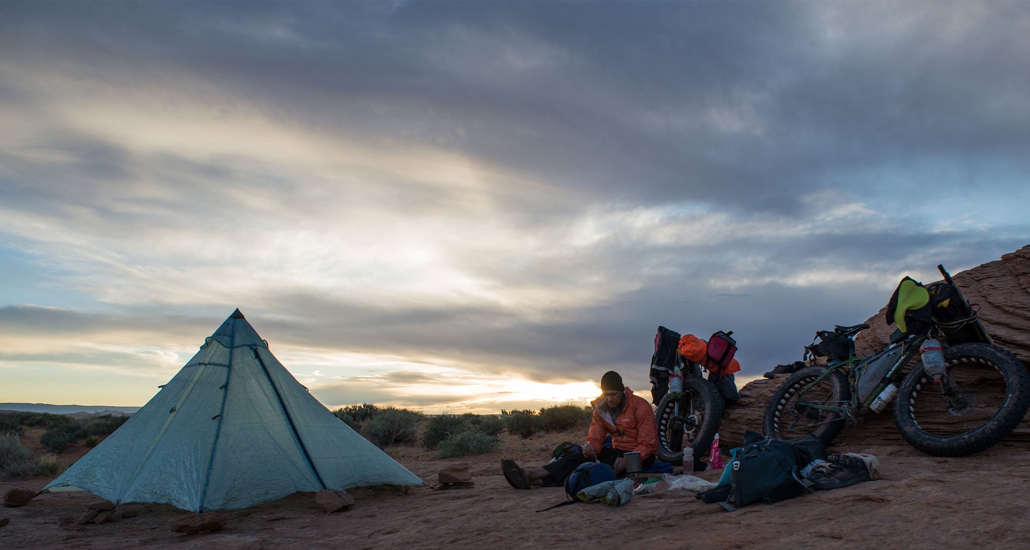 Bikepackers sit next to ultralight tent