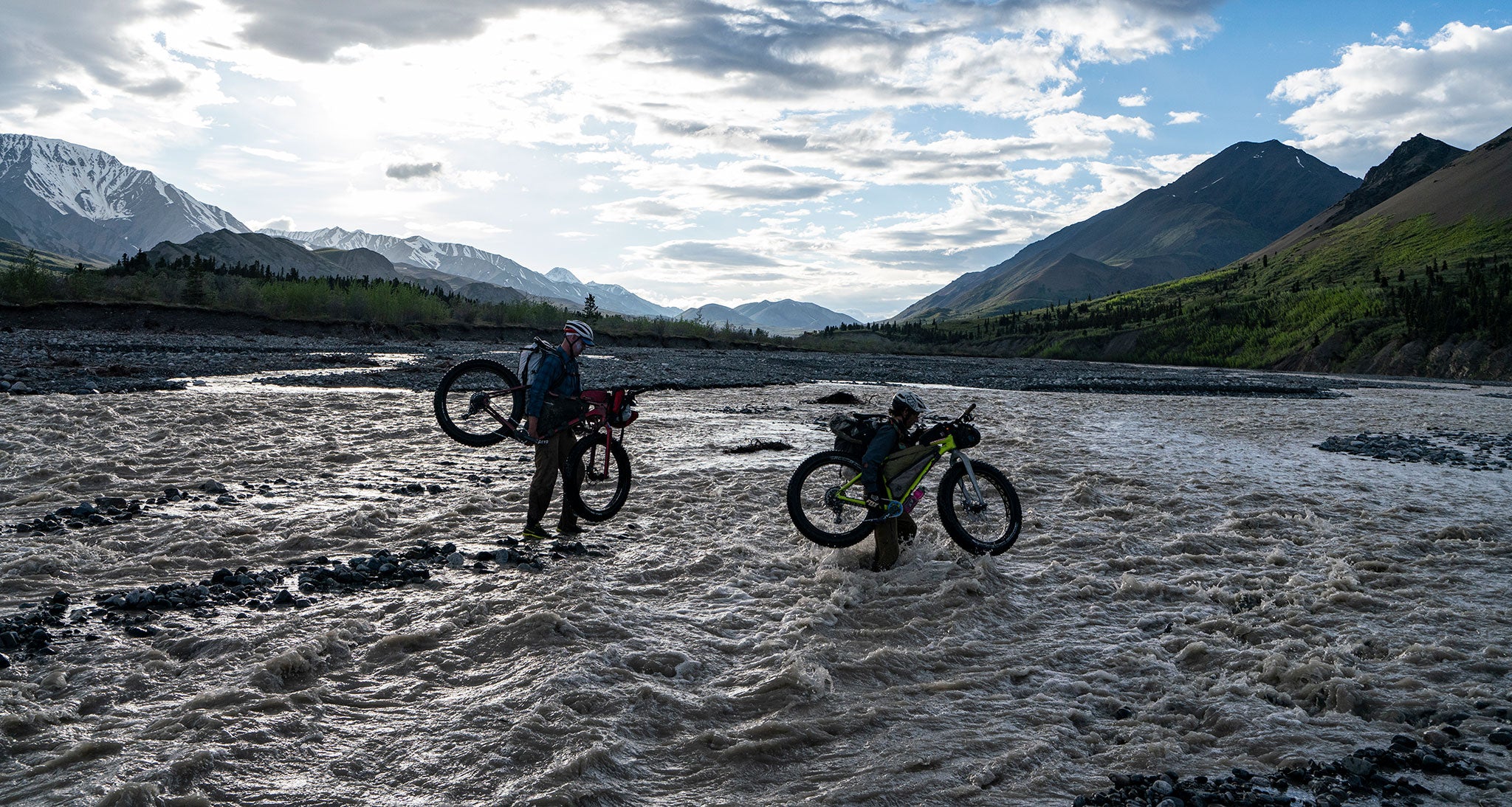 Ultralight bikepackers crossing a river while carrying bikes