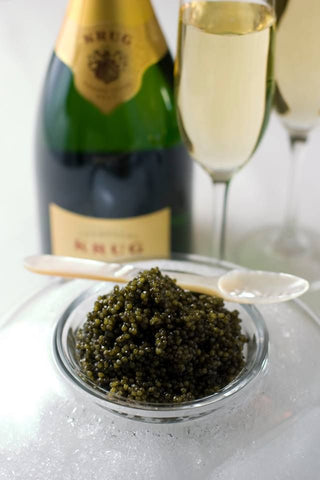 a bowl of caviar is in front of a wine   