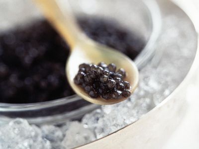 a spoon of caviar and a cup of caviar on ice
