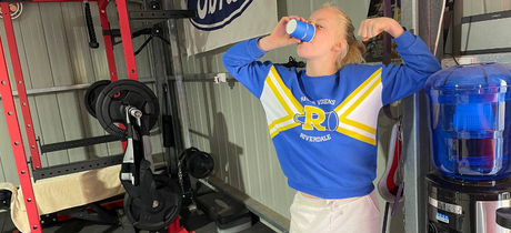 young girl drinks from her water cooler in dad's man cave