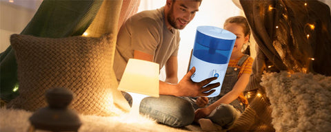 Man and daughter in a fort at home holding water cooler.