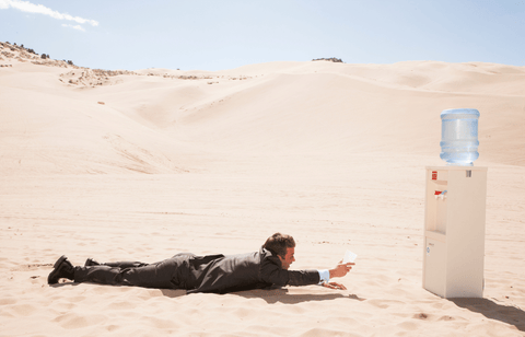 Dehydrated man in business suit searches for chilled water in the desert.