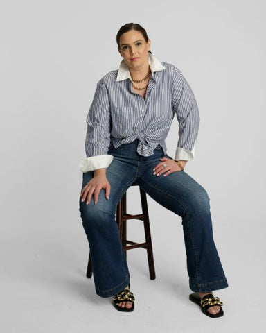 model on stool wearing striped shirt and jeans