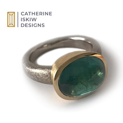 Large green tourmaline cabochon ring in an 18k yellow gold bezel and a white gold shank with Catherine Iskiw Designs logo.