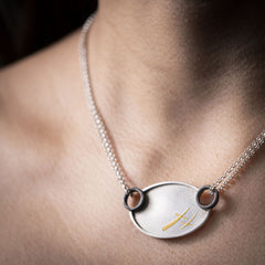 A stunning steel, silver and gold XOXO necklace handmade by Zink Metals