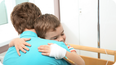 Father and son hugging in a hospital. Child has an IV in his hand