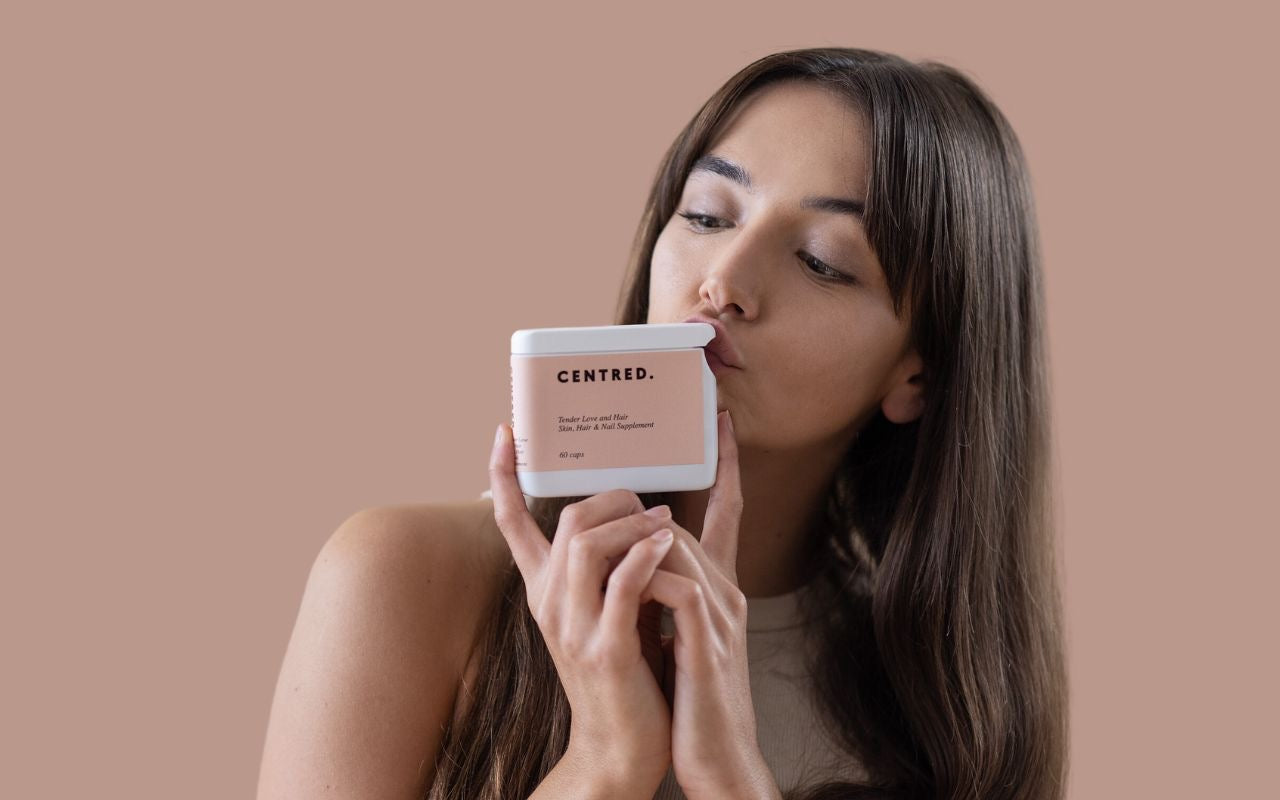 woman kissing a box of hair growth vitamins 