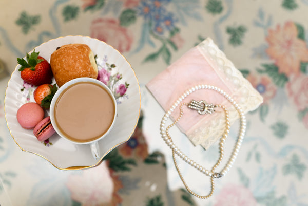 Jewelry and a porcelain tea cup with pastries and fruit