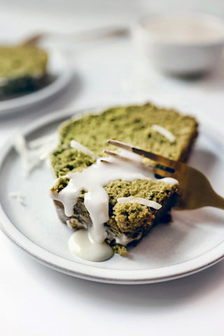 Cutting a piece of coconut matcha cake with icing