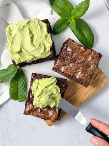 Brownies being spread with a green matcha mint frosting