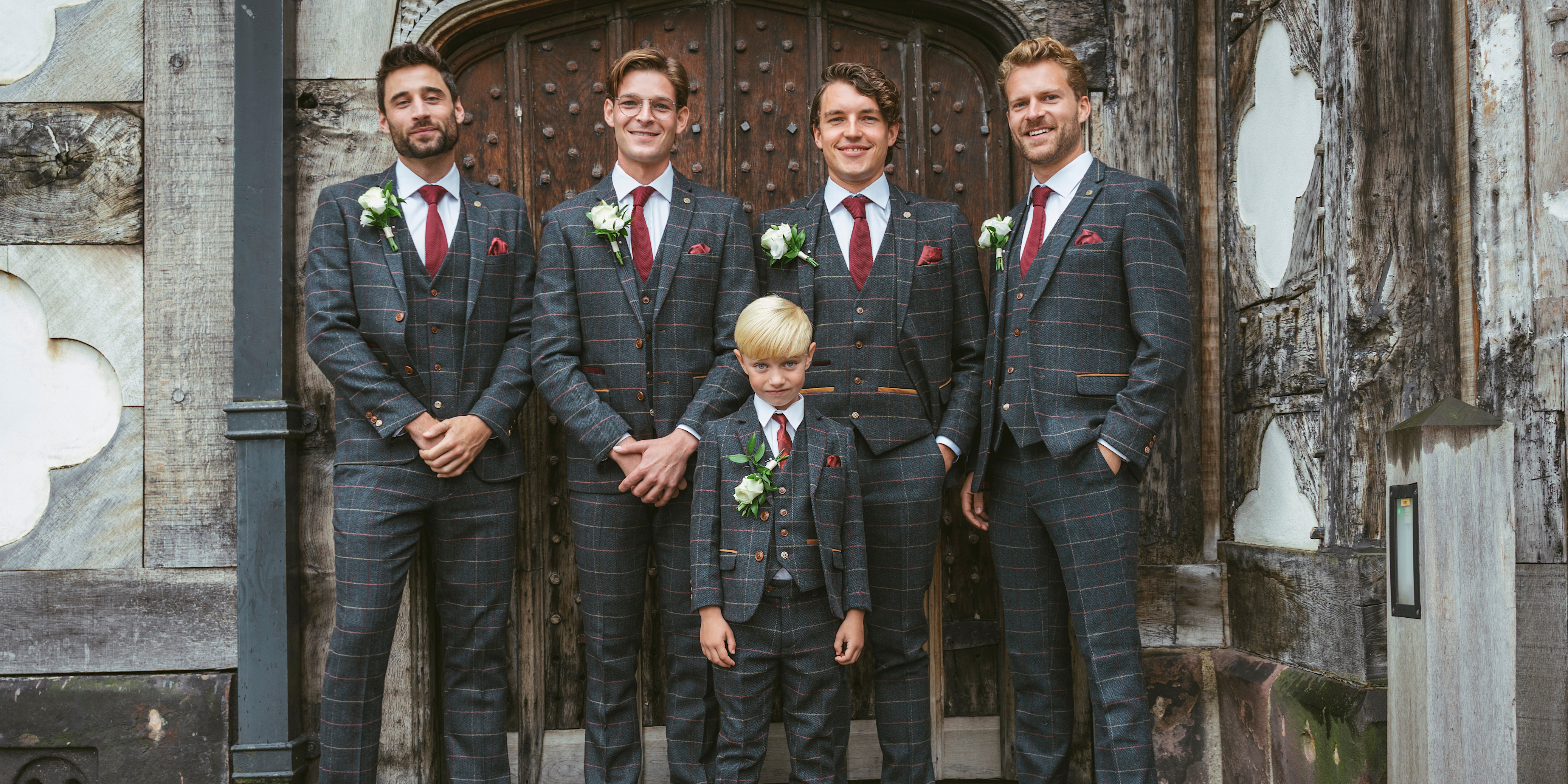 Groomsmen and young boy wearing navy checked tweed three piece suits on wedding day