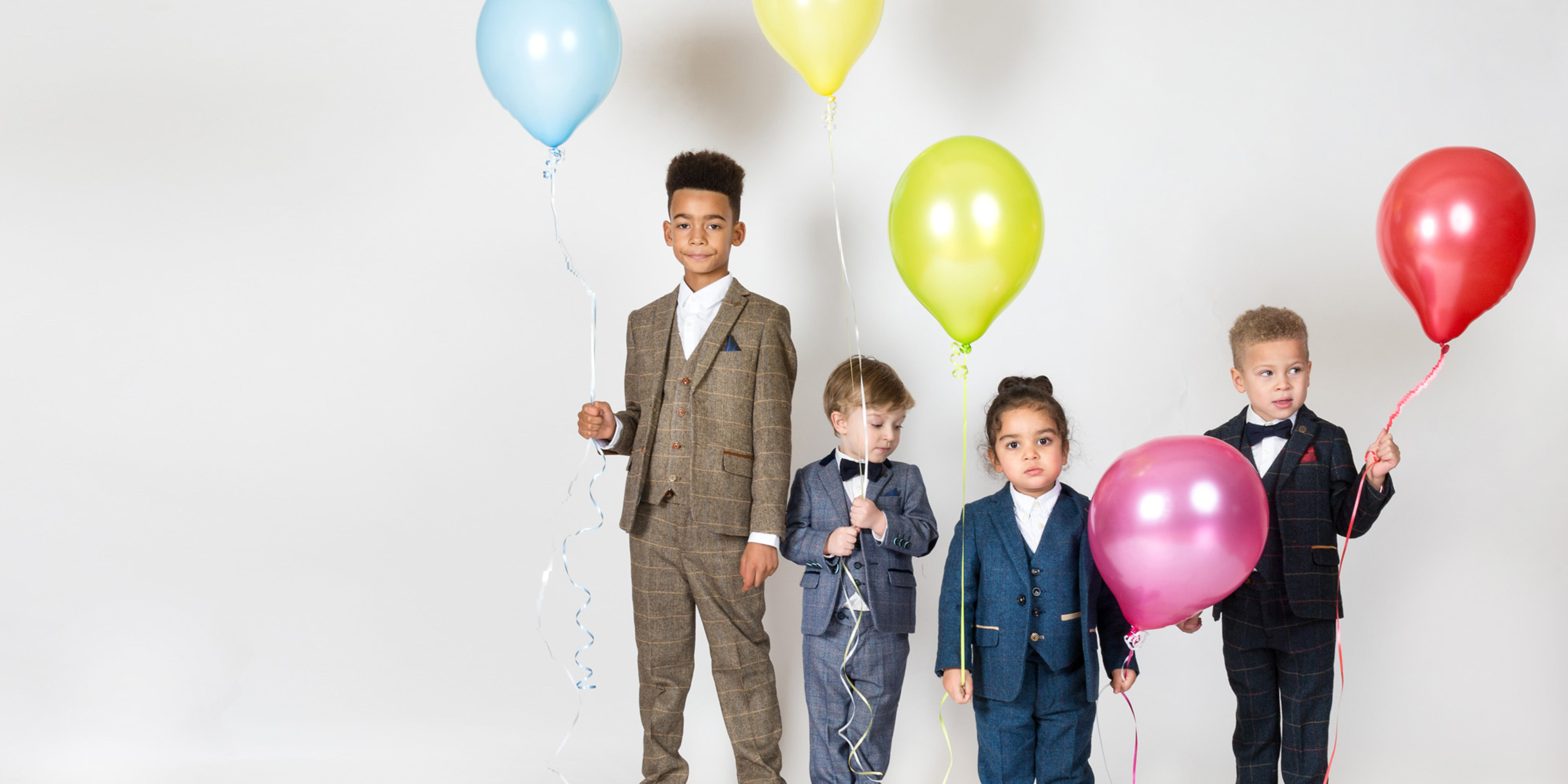 children wearing boys three piece wedding suits holding balloons