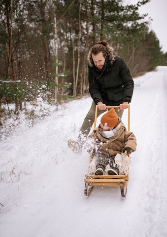 father pushing kid on a sled