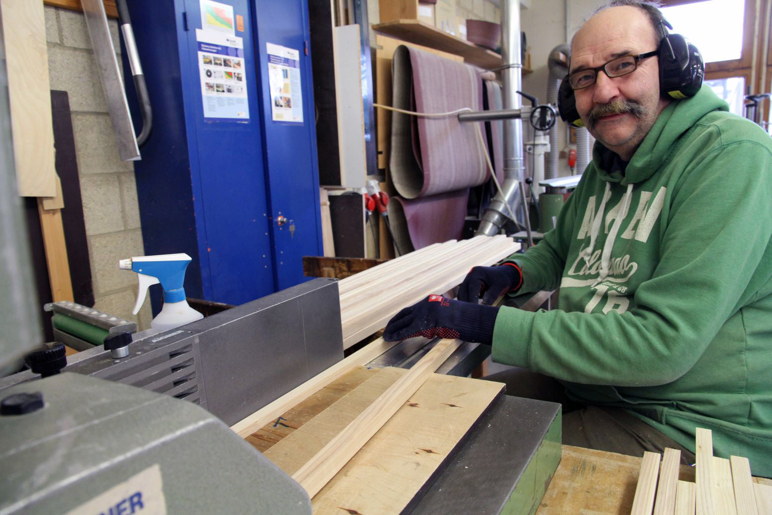 A man in a workshop uses a machine to plane and sand raw wood for Metalog Tool's award-winning and sustainable training tools