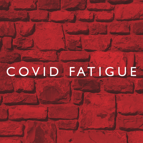 COVID Fatigue is written in white lettering in front of a red brick background