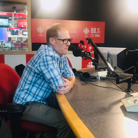 Wade Repta is sitting at a desk, speaking into a microphone during a CBC radio interview 