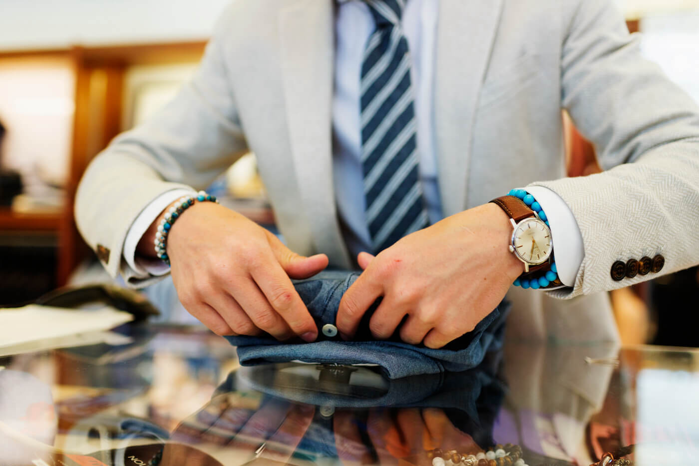 Seller folding dress shirt on table in clothing store