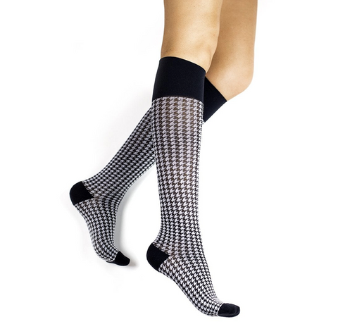 pair of feet wearing knee-high compression socks with black and white houndstooth print