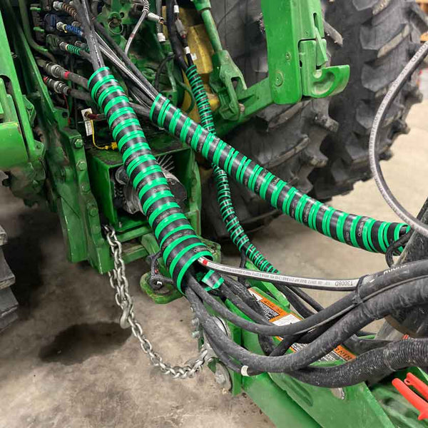 Hose Boss spiral hose wrap in green, protecting the hoses on a John Deere Planter.