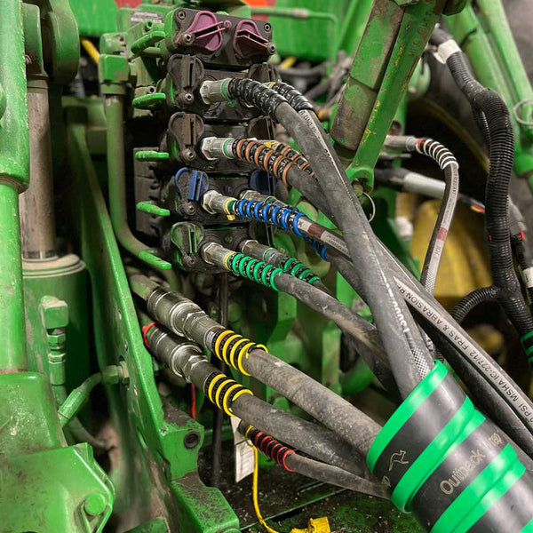 A close up image of multiple hydraulic hoses bundled together and protected with an Outback Wrap Hose Boss.